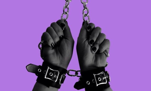 photo showing chained and cuffed hands with painted nails