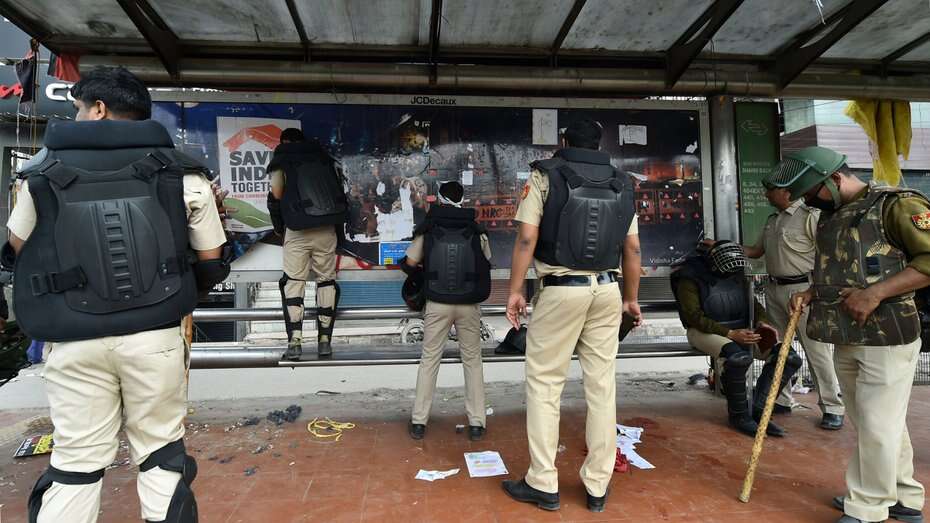 Delhi Police personnel remove posters at Shaheen Bagh protest site.