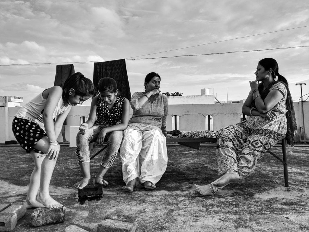 Women at Leisure: Sushma and Aasha enjoy a break on Sushma's terrace before they both return to their kitchens to prepare dinners for their families. Their daughters are enjoying each other’s company.