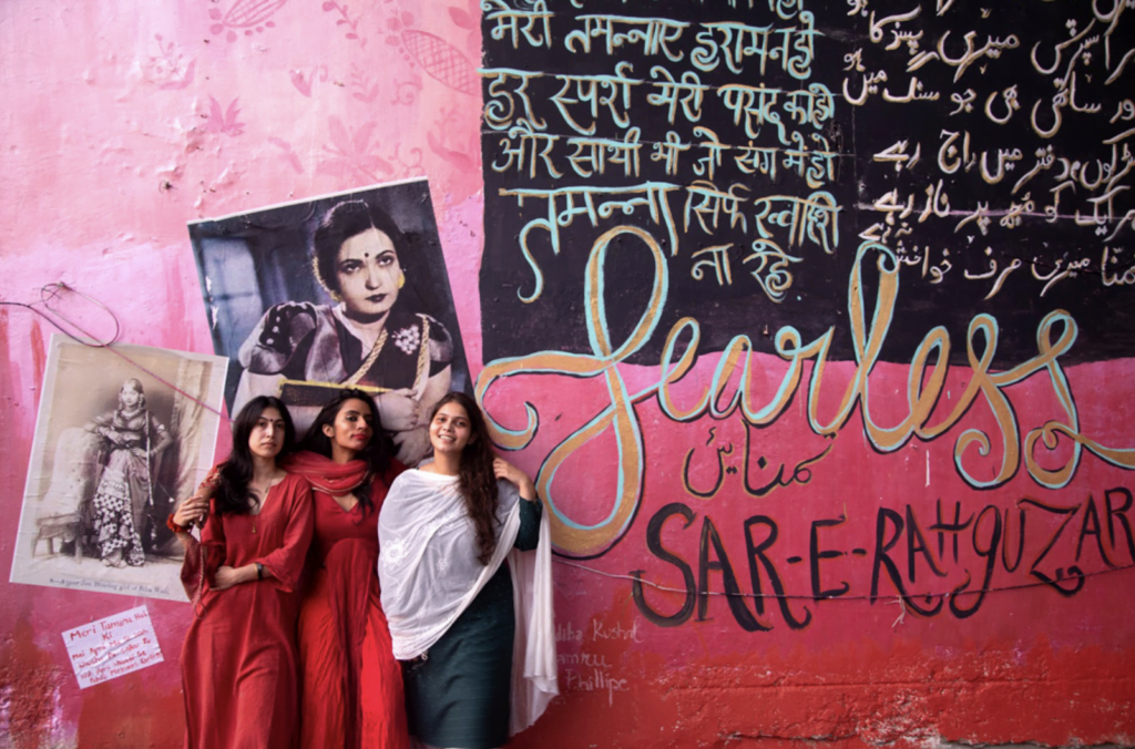 Shilo Shiv Suleman standing against a wall with two girls on either side