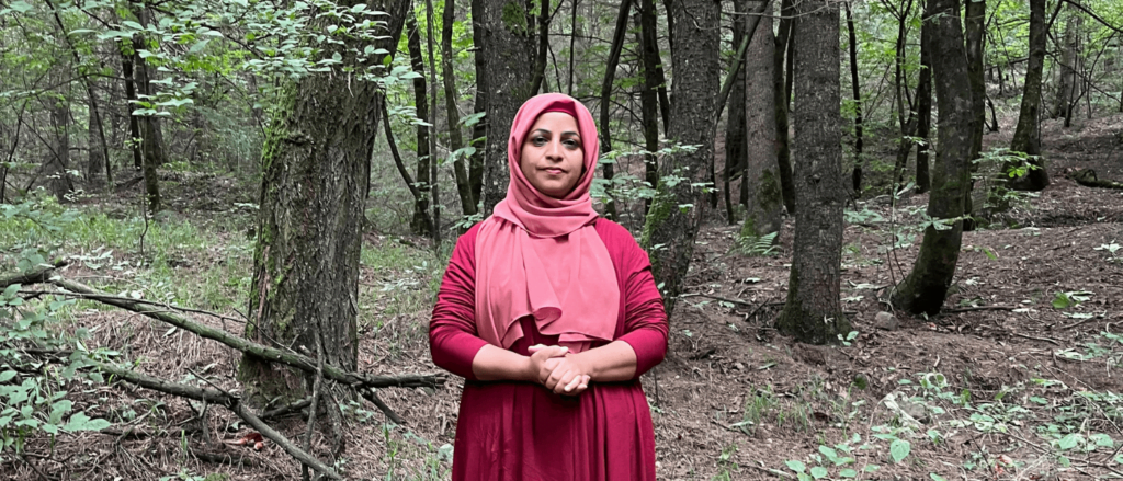 Aliya, wildlife rescuer standing, posing for the camera in a forest