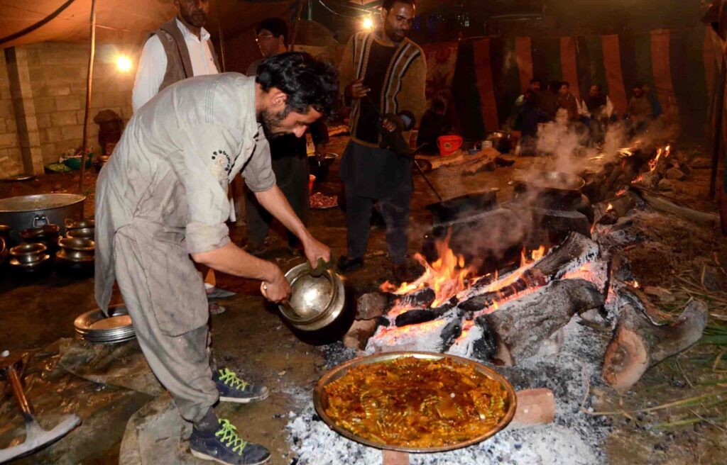 Waza in a grey dress near the fire cooking cuisines. 