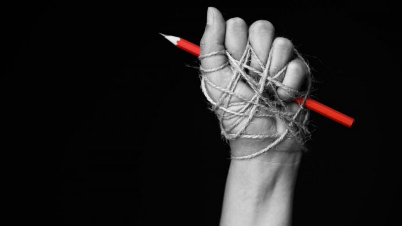 Hand with pencil tied with ropes