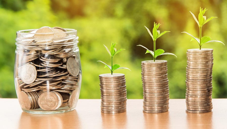 Coins in a jar and stacks of coins with saplings sprouting from them