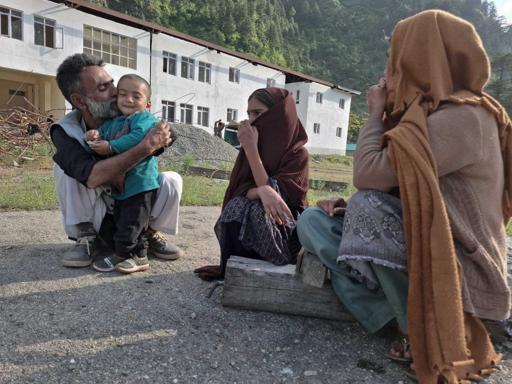 A father gently kisses his daughter in a shelter camp at Government Degree College, Boniyar, where the displaced families were given refuge during the shelling. Credit: Umer Farooq