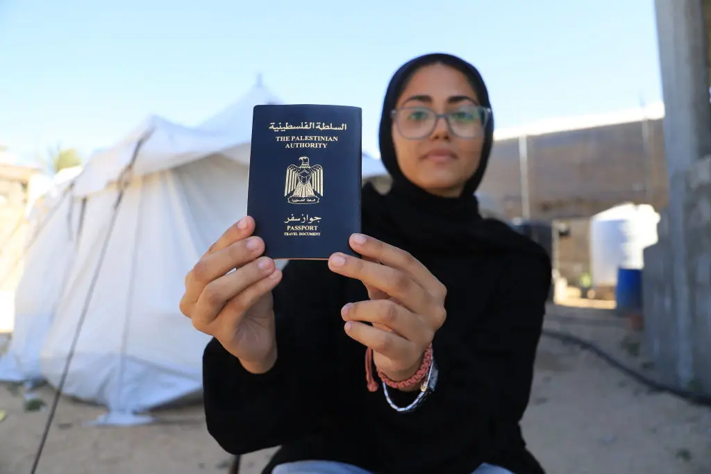 Nur Al Rimlawi, a Palestinian artist in Gaza, holds her Palestinian passport, on which she’s painted countries she wishes she could visit, on Sept. 10, 2024.